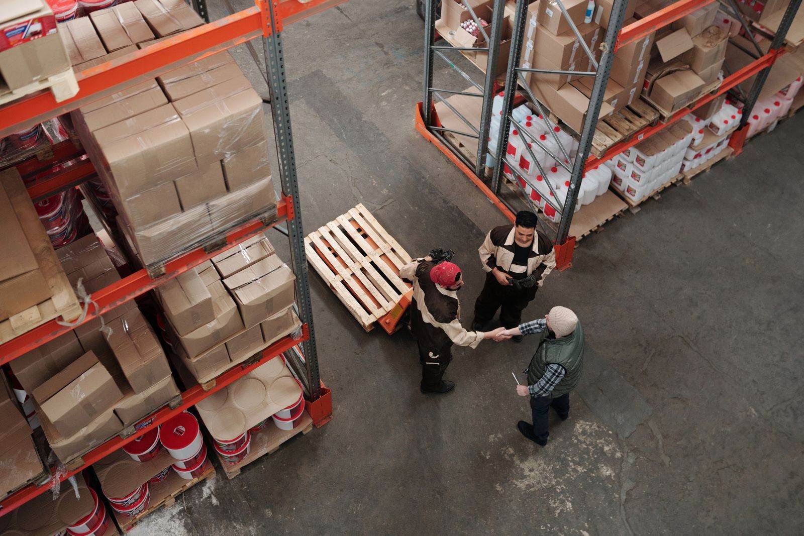 High angle view of workers shaking hands in a warehouse, symbolizing teamwork and logistics