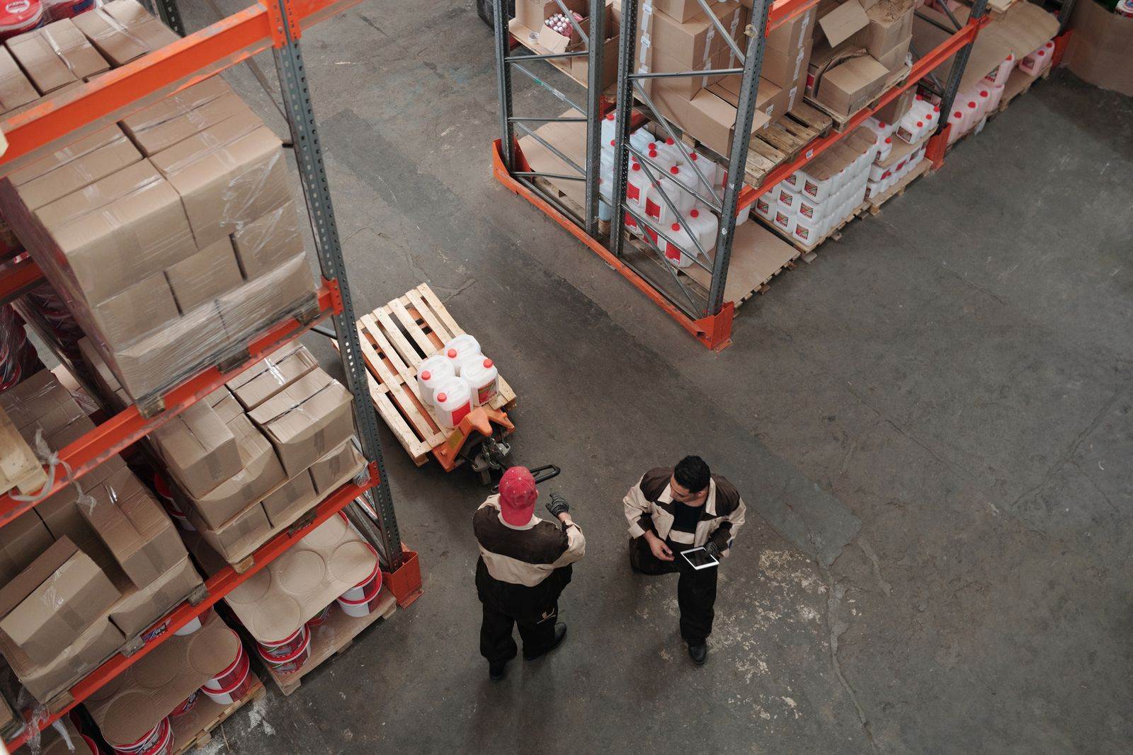 High angle view of warehouse workers organizing inventory with pallets and shelves